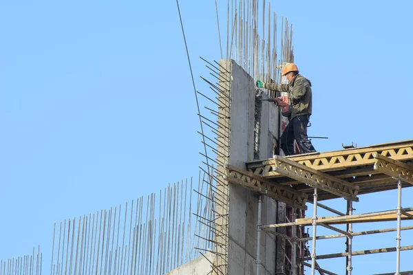 Mavi gökyüzüne karşı kurulumcular metal yapılar topluyor. Kavram - yükseklerde çalışmak, metal yapıların toplanması