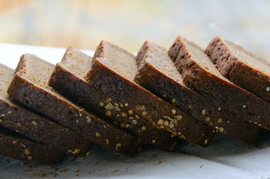 Bir somun siyah ekmek parçalara ayrılmış ve kişniş serpiştirilmiş. Kavram - sağlıklı doğal gıda, diyet