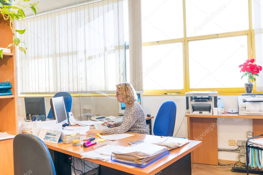 cheerful beautiful freelancer middle aged woman wearing eyeglasses, sitting in front of computers in her office, receive courier service