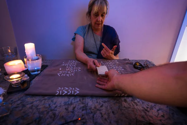 Tarot cards. Woman sits near a fortune teller desk with Tarot cards and candles. Divination and clairvoyance.