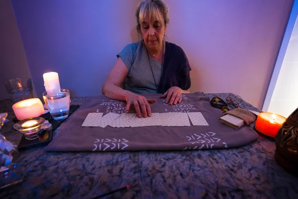 Tarot cards. Woman sits near a fortune teller desk with Tarot cards and candles. Divination and clairvoyance.