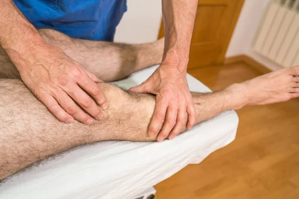 Doctor physiotherapist assisting a male patient while retropatellar crepitation ; of patient in a physio room, rehabilitation physiotherapy concept.