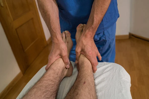 Médico fisioterapeuta assistindo um paciente do sexo masculino, dando verificação da pelve do paciente em uma sala de fisioterapia, conceito de fisioterapia de reabilitação . — Fotografia de Stock