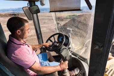 güneşli bir günde çalışan tekerlekli yükleyici operatörü