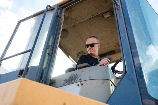 wheel loaders operator with sunglasses working hard in a sunny day