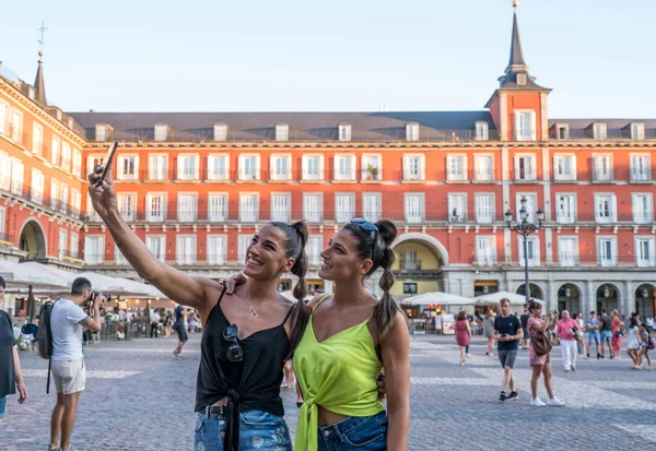 Bonitas hermanas gemelas tomando selfie en la calle en un día soleado . — Foto de Stock