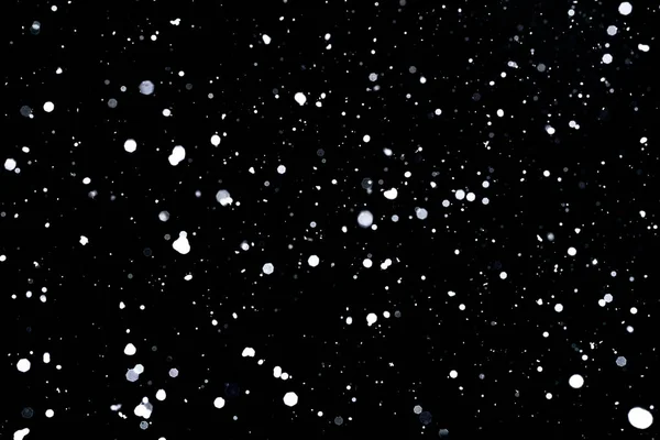 Schneefall auf schwarzem Hintergrund Schneeflocken fliegen in der Luft. — Stockfoto