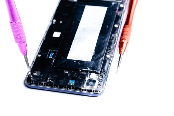close-up photos showing the process of repairing a broken mobile phone with a screwdriver in the laboratory for repair of mobile equipment and cell phones