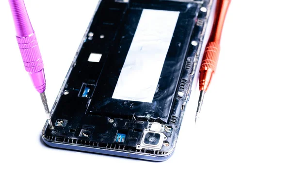 mobil ekipman ve cep telefonlarının onarımı için laboratuvarda bir tornavida ile kırık bir cep telefonu tamir sürecini gösteren yakın çekim fotoğraflar