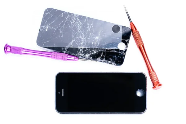 mobil ekipman ve cep telefonlarının onarımı için laboratuvarda bir tornavida ile kırık bir cep telefonu tamir sürecini gösteren yakın çekim fotoğraflar