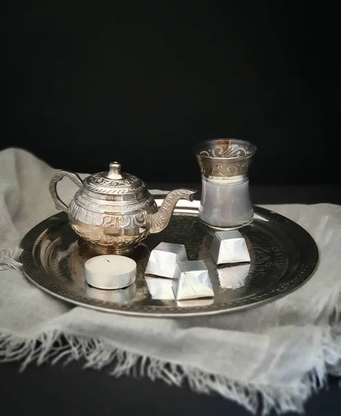 Gümüş süs tepsisi, küçük gümüş çaydanlık ve çay, süt, şeker ve gri güzel tekstil üzerine bir mum. Lezzetli çerez. Yemek fotoğrafı.