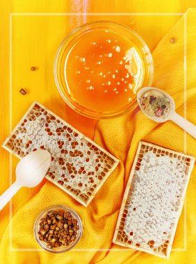 Bal fuarında arı ürünlerinin olduğu masa üstü, üst manzara. Organik, bağışıklık sistemini arttıran yüksek miktarda vitaminli doğal ürünler. Bal, parşömen, turuncu arka planda bal peteği