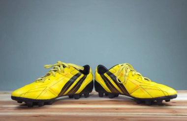 Bir çift eski futbol gri arka plan yumuşak ışık, ahşap bir yönetim kurulu yerleştirilen eski sarı futbol ayakkabı çizme
