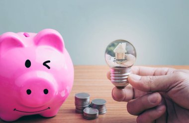 Bir ampul tutan bir adamın elini. tasarruf para sikke mülkiyet merdiven, ipotek ve gayrimenkul yatırım için bir ev concept kavram satın almak için planlama. kaydetme veya bir ev için yatırım,