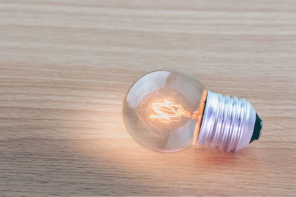 glowing bulb on the brown wooden background. Ideas to find good ideas to do business.