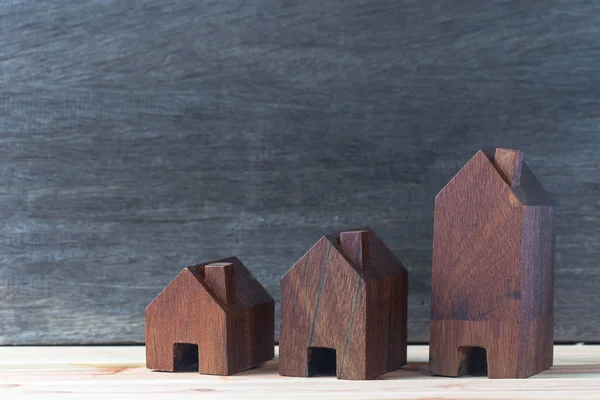 Tres casas modelo colocadas en suelo de madera, fondo de madera gris — Foto de Stock