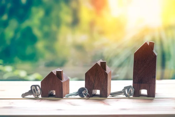 Petite maison avec clé placée sur une table en bois sur fond naturel — Photo