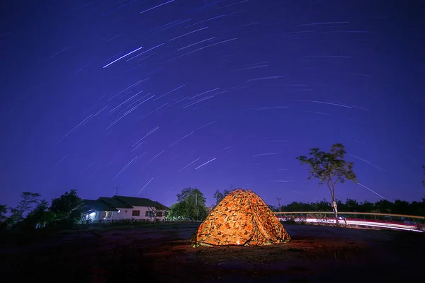 Tent camping in the forest with starry night sky and the moon.