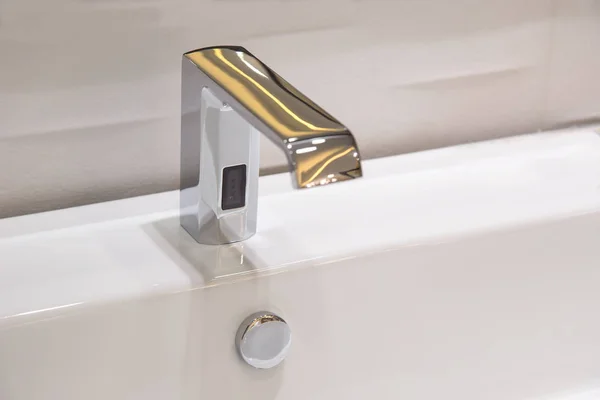 Robinet de salle de bain en chrome poli alimenté automatiquement par capteur . — Photo