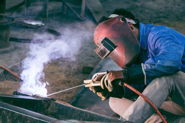 Güvenlik maskesi ile sanayide kaynak çeliği çalışan işçi kaynakçı