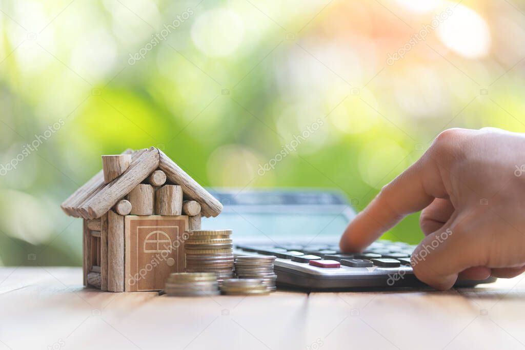 The man's hand pressing the calculator. coins cash money in piles, planning savings money of coins to buy a home concept for property, mortgage and real estate investment.to buy a house.