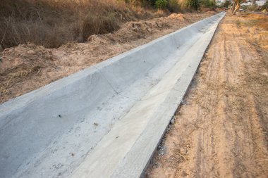 Kanalizasyon için beton drenaj tepsileri. Şehirde drenaj. Kanalizasyon inşaatı. Yağmur suyu drenajı için kanalizasyon tepsisi. Yağmurdan sonra yol kenarındaki kanalizasyona..
