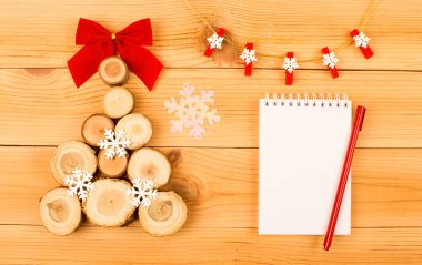 Noel ağacı ahşap kesim bir kırmızı yay ile üzerinden. Bunun yanında kırmızı kalemle dilek yazmak için beyaz bir dizüstü bilgisayardır. Çelenk kar taneleri ile yukarıda yer alır. Her şey bir ahşap zemin üzerinde yer alır.