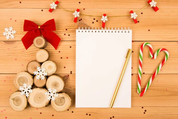 Bir kırmızı yay ve beyaz kar taneleri ile ahşap Noel ağacı. Bunun yanında notlar ve altın rengi bir kalem için beyaz bir dizüstü bilgisayardır. Çelenk kar taneleri ile yukarıda yer alır. Kırmızı yıldız sparkles ve şeker kalp çevresinde. Tüm bu ahşap backgro üzerinde