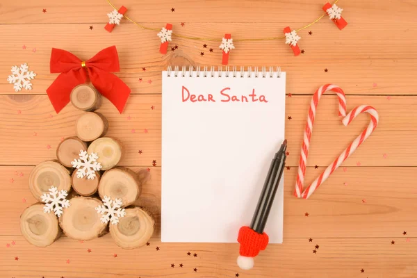 Noel ağacı ahşap yapılmış kar taneleri kesim gördüm. Yakınlarda bir defter ile Noel Baba, kırmızı bir işaretleyici ve şekerler yapılan bir kalp için yazmak için bir yer olduğunu.