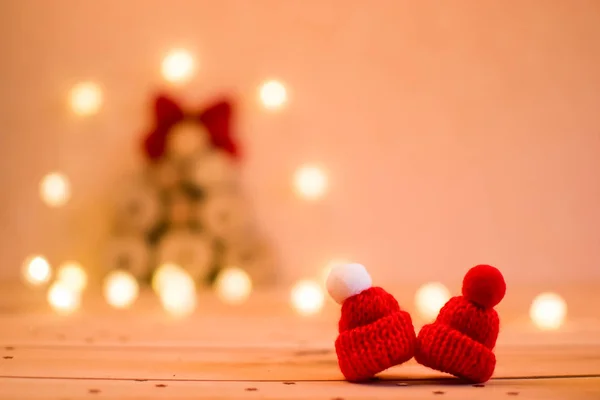 Bulanık bir Noel ağacı ışıkları ahşap arka plan üzerinde çevrili arka plan üzerinde iki kırmızı şapka.