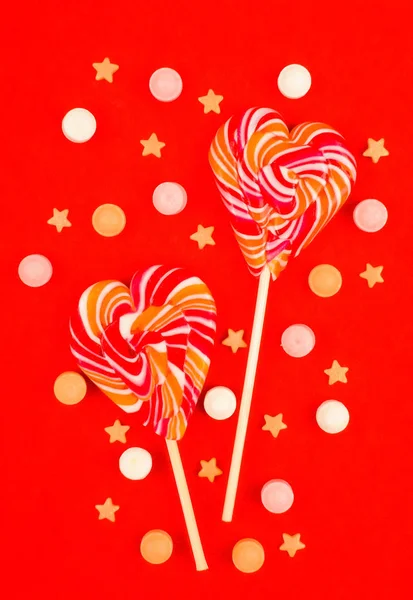 Lolipop bir çubuk kırmızı bir arka plan üzerinde kalp şeklinde. Şeker.