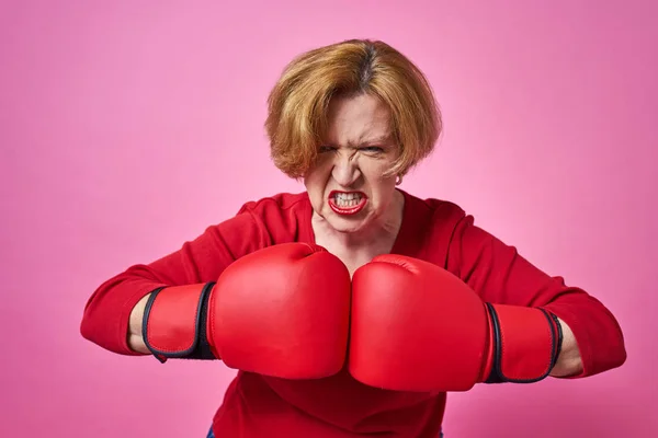 Woman aged in boxing gloves. The concept of the fight against old age.