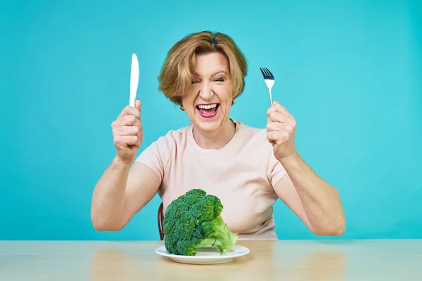 An aged woman is about to eat a vegetarian dish. Funny old woman on a broccoli diet. Stock Image