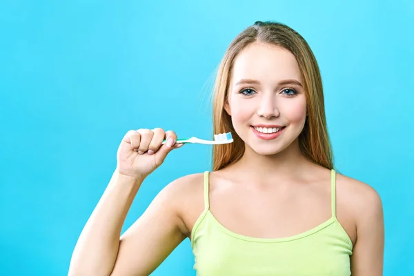 Portret van aantrekkelijke Kaukasische Glimlachende vrouw geïsoleerd op blauwe studio schot haar tanden borstelen — Stockfoto