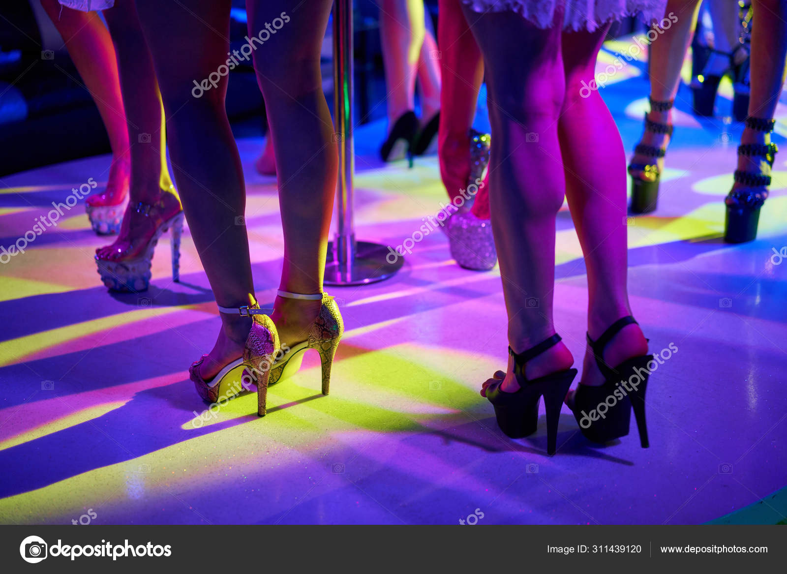 Young sexy woman pole dancing striptease with pylon in night club