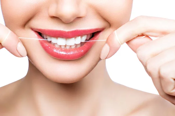 Ung vacker kvinna är engagerad i rengöring tänder. Vackra leende friska vita tänder. En flicka håller en tandtråd. Begreppet munhygien. — Stockfoto
