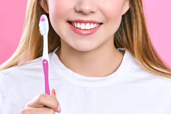 Joven hermosa mujer se dedica a la limpieza de dientes. Hermosa sonrisa dientes blancos sanos. Una chica sostiene un cepillo de dientes. El concepto de higiene bucal. Imagen promocional para una estomatología, clínica dental . — Foto de Stock