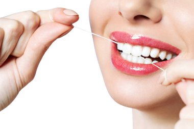 Genç güzel kadın diş temizliği yapan. Güzel gülümseme sağlıklı beyaz dişler. Bir kız diş ipi tutar. Ağız hijyeni kavramı. Bir diş kliniği için promosyonel görüntü.