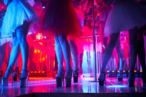 Jonge sexy vrouwen paaldansen striptease in nachtclub. Mooi naakt stripper meisje op het podium. Mooie vrouwelijke benen in hoge hakken schoenen strips — Stockfoto