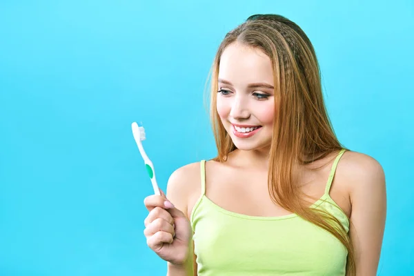 Jonge mooie vrouw is bezig met het schoonmaken van tanden. Mooie glimlach gezonde witte tanden. Een meisje houdt een tandenborstel. Het concept van mondhygiëne. Promotionele afbeelding voor een stomatologie, tandheelkundige kliniek — Stockfoto