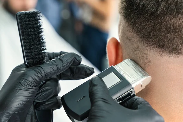 Klient zakładu fryzjerskiego. Człowiek obcinający brodę elektryczną maszynką do golenia — Zdjęcie stockowe