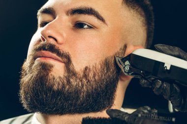 Berber dükkanı müşterisi. Adamın sakalını elektrikli jiletle kestiriyorlar.