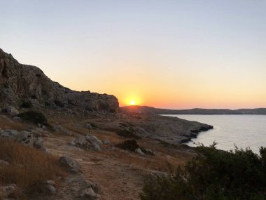 güneş doğar ve arkadan dağlar, deniz, kıyı şeridi ufukta bir boğucu yaz günü planlanmaktadır görülür