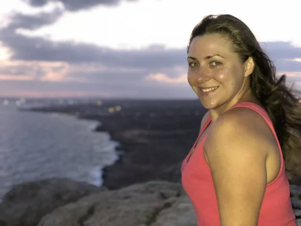 light-skinned girl with shining eyes enjoys the sunrise on the top of the hill on the coast