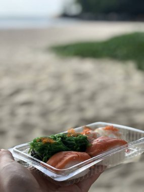 Tay suşi deniz ve kıyı şeridi öğleden sonra karşı bir kadının Palm'da