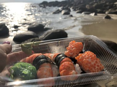 Tay suşi deniz ve kıyı şeridi öğleden sonra karşı bir kadının Palm'da