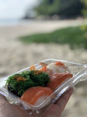 Tay suşi deniz ve kıyı şeridi öğleden sonra karşı bir kadının Palm'da