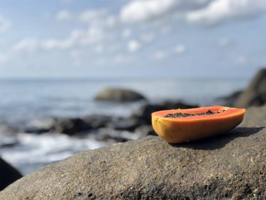 öğleden sonra bulutlu mavi gökyüzü ve deniz karşı bir taş üzerinde sulu taze Tay papaya