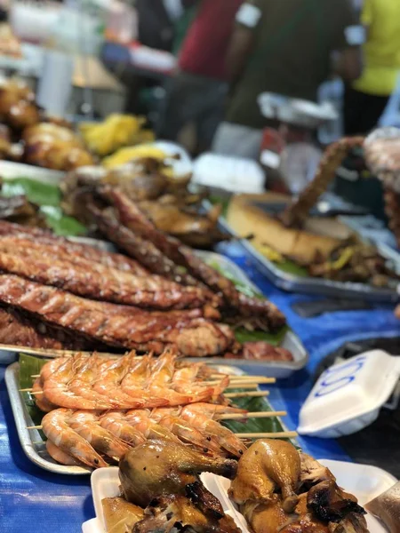 Thai night market with national food: fried fish, sushi, rice sweets, skewers, sushi, seafood
