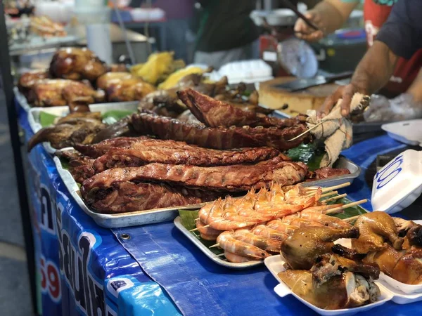 Thai night market with national food: fried fish, sushi, rice sweets, skewers, sushi, seafood